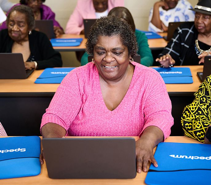 Woman using a laptop in a computer lab, along with others