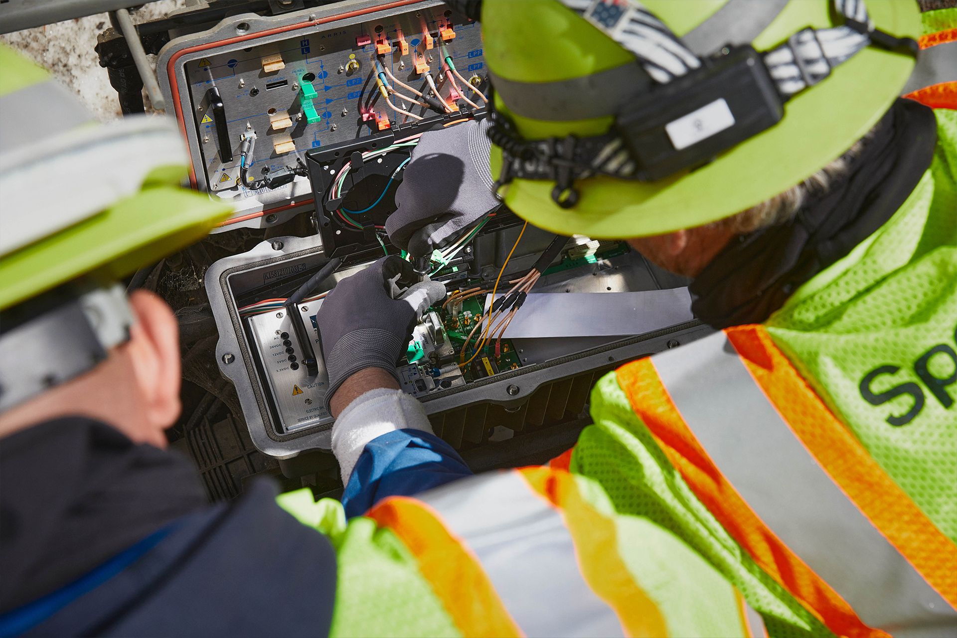 Spectrum field technicians working on a node, viewed from behind