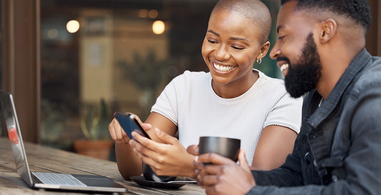 African American couple using their cell phones, smiling